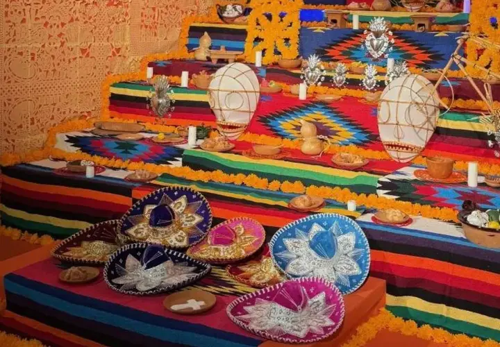 Un vibrante altar de los muertos en una casa de México, adornado con sombreros, flores de cempasúchil y ofrendas.