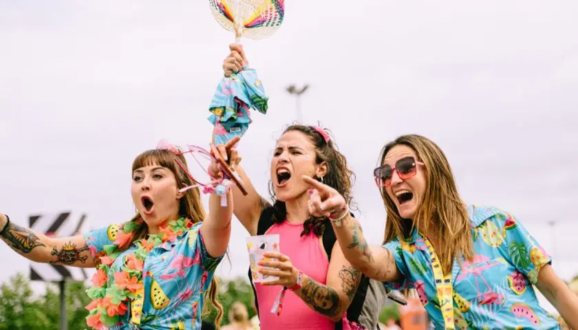 Tres chicas con camisas tropicales y collares de flores, riendo y bailando. ¡Me encanta el espíritu de las tuenti's!