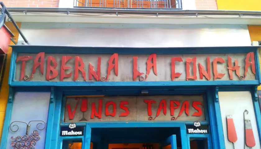Fachada de la Taberna La Concha, con letrero rojo y azul. Ofrece vinos y tapas. ¡Las opiniones de la taberna La Concha son muy buenas!