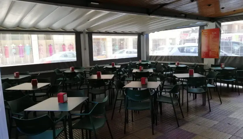 Terraza de bar con mesas y sillas verdes, ideal para saber donde comer en Cullera bien y barato.