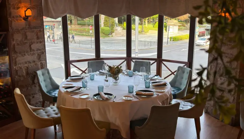 Mesa elegante lista para una cena en la corte de Pelayo, con vistas a la calle y un parque.