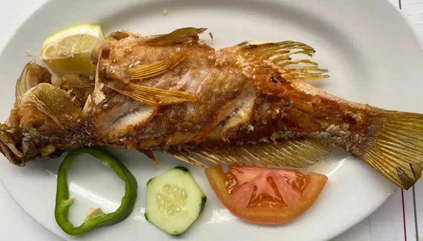 Pescado frito entero, servido con rodajas de limón, pimiento verde, pepino y tomate. ¡Una excelente opción de donde comer en El Hierro!