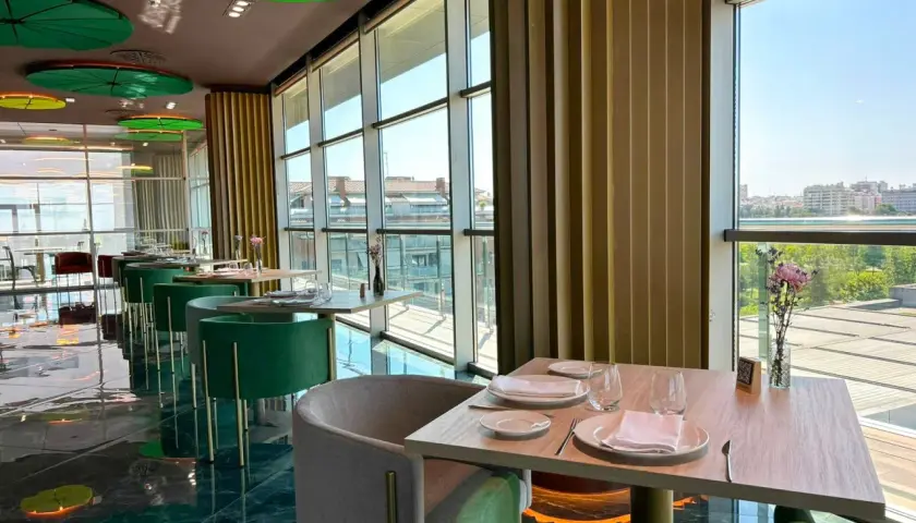 Mesas elegantemente puestas en un restaurante moderno con vistas panorámicas. Un lugar ideal para disfrutar de los mejores restaurantes Badajoz.