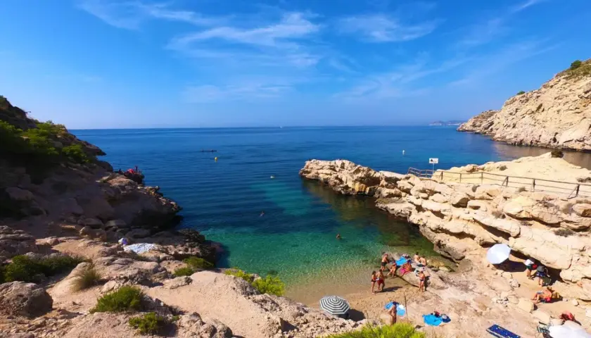 Un día soleado en el racó del conill, con gente disfrutando de las aguas cristalinas y la arena dorada.