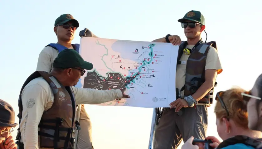 Guías explican un mapa de la Amazonía, compartiendo valiosas opiniones de restaurante amazónico para una aventura inolvidable.