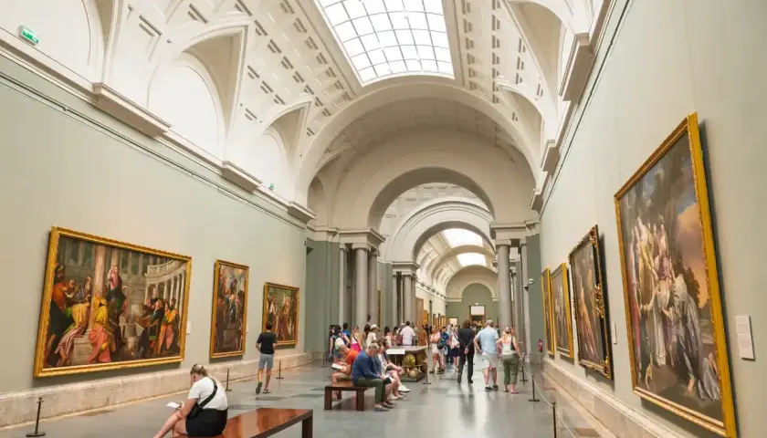 Gente disfruta del arte en un museo, celebrando el **18 de mayo, Día de los Museos**.