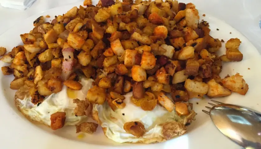 Plato de huevos fritos con patatas y pan tostado, ideal para leer las opiniones de bar restaurante Casa Goyo.