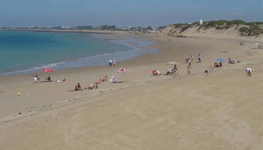 Gente disfruta del sol en la playa de Punta Candor, Rota. ¡Un lugar ideal para relajarse y leer opiniones positivas!