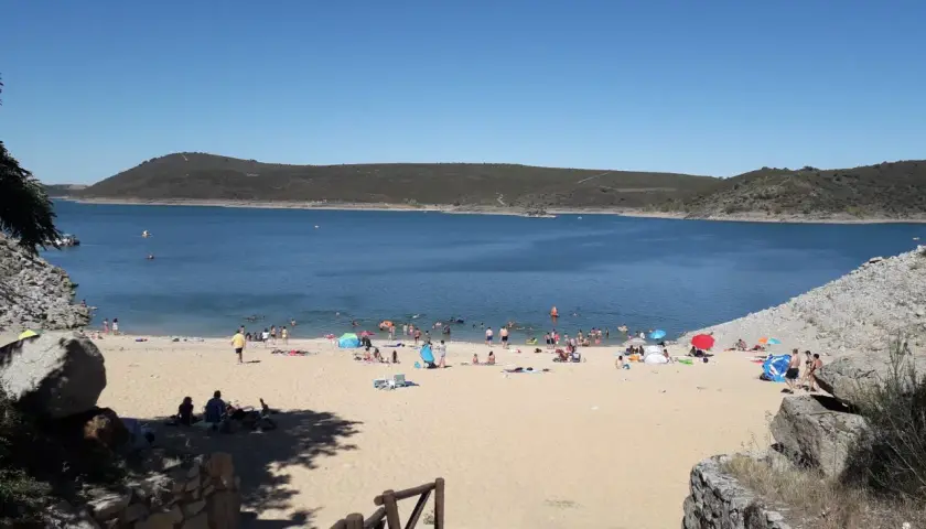 Gente disfrutando del sol y el agua en la playa fluvial de Ricobayo, un día perfecto para refrescarse.