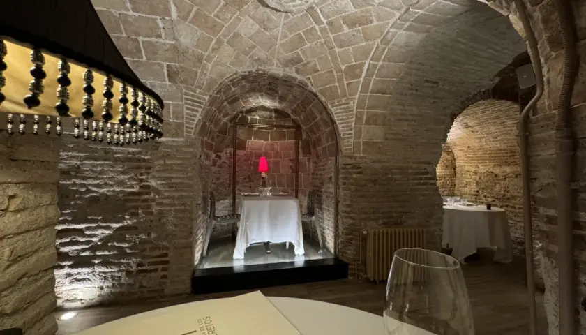 Menú de la Bodega de los Secretos en un ambiente rústico con arcos de piedra y mesas preparadas.