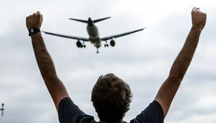 Persona con brazos en alto celebra la llegada de un avión en el mirador de aviones de El Prat.