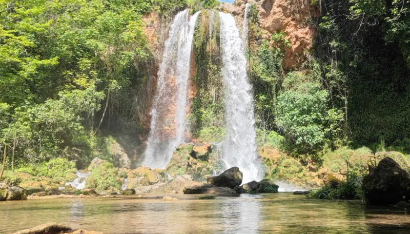 Cascada imponente cayendo en el lago de Anna, rodeada de vegetación exuberante y rocas cubiertas de musgo.