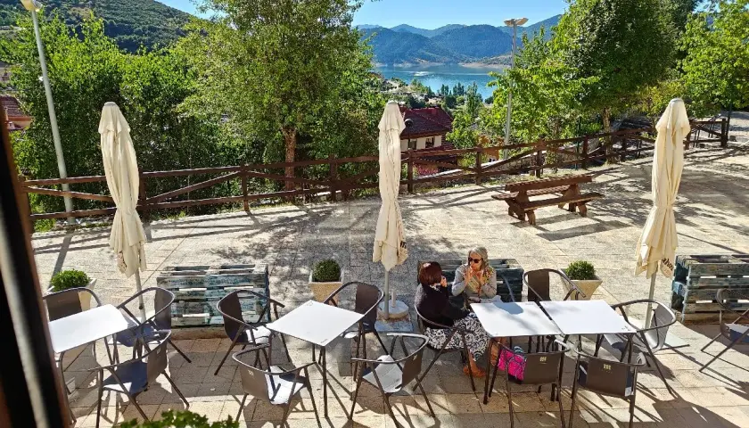 Terraza de restaurante con vistas al embalse. Ideal para saber donde comer en Riaño. Mesas, sillas y sombrillas listas para disfrutar.
