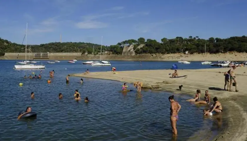 Gente disfrutando de un día soleado en la playa, ¡quién diría que en Madrid hay playa! Barcos y bañistas en un día perfecto.