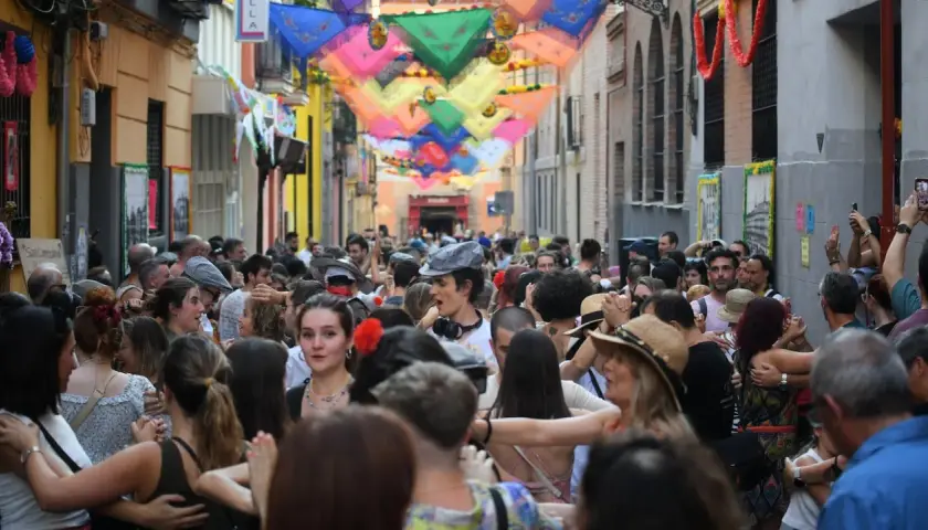 Gente bailando en las fiestas San Cayetano Madrid, con coloridas telas adornando la calle.