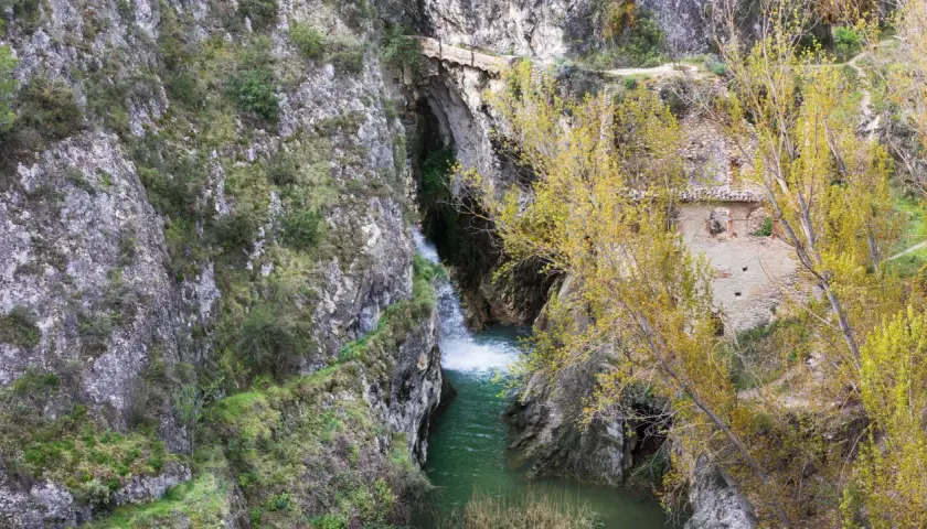 Cascada y ruinas en un cañón. Para saber benilloba como llegar, sigue el sendero entre las rocas y la vegetación otoñal.