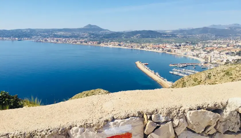 Vista panorámica de la bahía y el puerto deportivo, con el faro del Cabo de San Antonio al fondo.