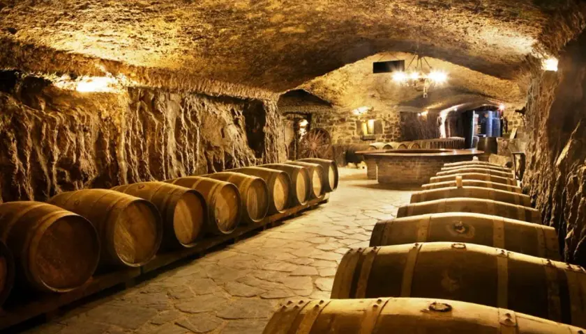 Antiguas barricas de roble esperan en esta bodega subterránea, perfecta para una visita a bodegas.