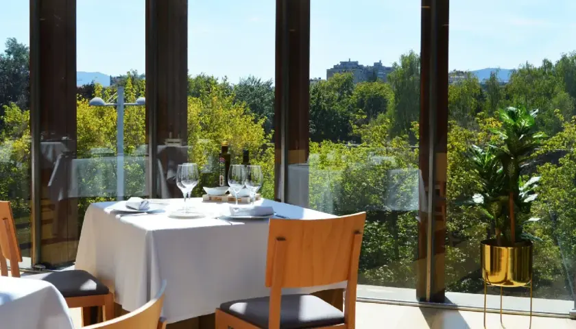 Elegante mesa puesta en un restaurante con vistas a la naturaleza, ideal para descubrir los mejores restaurantes en pueblos cerca de Pamplona.