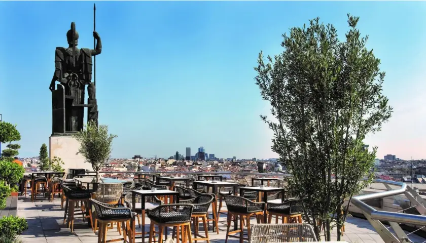 Terraza Bellas Artes Madrid con vistas a la ciudad, una estatua imponente y mesas listas para disfrutar.