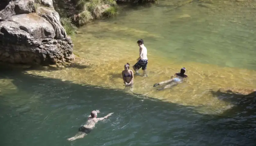 Gente disfrutando de un día en las playas cerca de Zaragoza, nadando y refrescándose en aguas cristalinas.