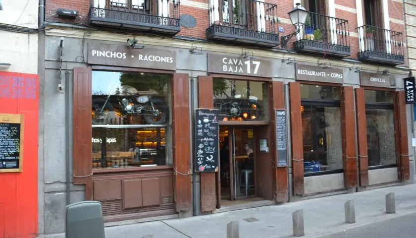 Fachada de Cava Baja 17, un restaurante con una moto vintage expuesta en el escaparate.