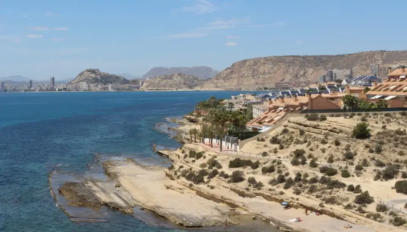 Vista de la cala Cantalar en Alicante, con casas en la ladera y el mar azul.