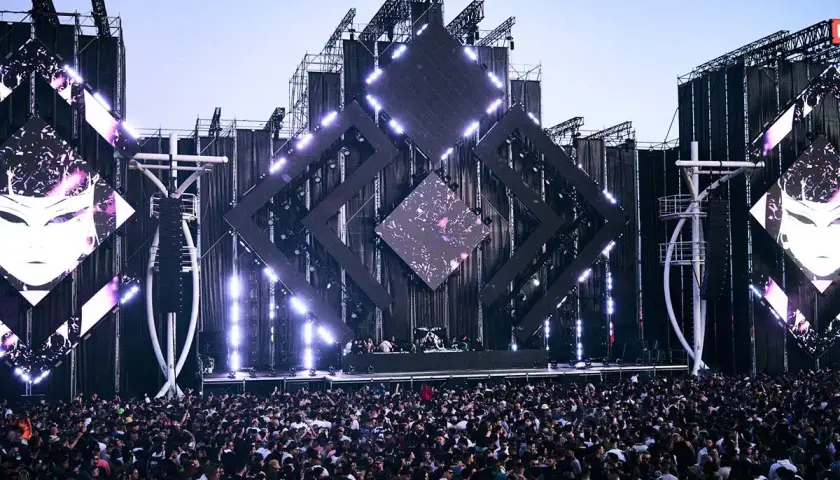 Multitud vibrante en un festival de música, escenario futurista con luces y pantallas. Una escena épica para tu summer story 2026.