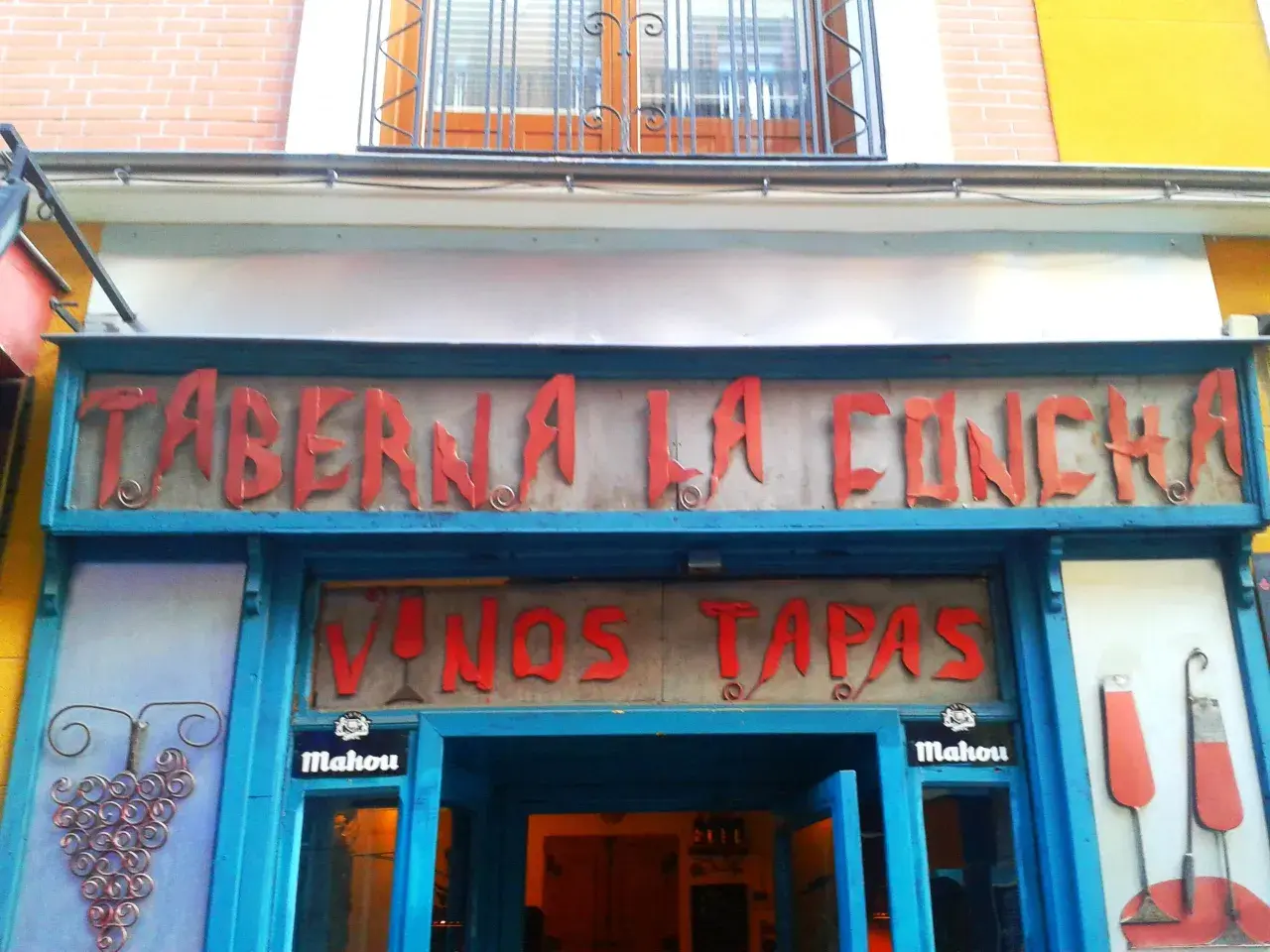 Fachada de la Taberna La Concha, con letrero rojo y azul. Ofrece vinos y tapas. ¡Las opiniones de la taberna La Concha son muy buenas!