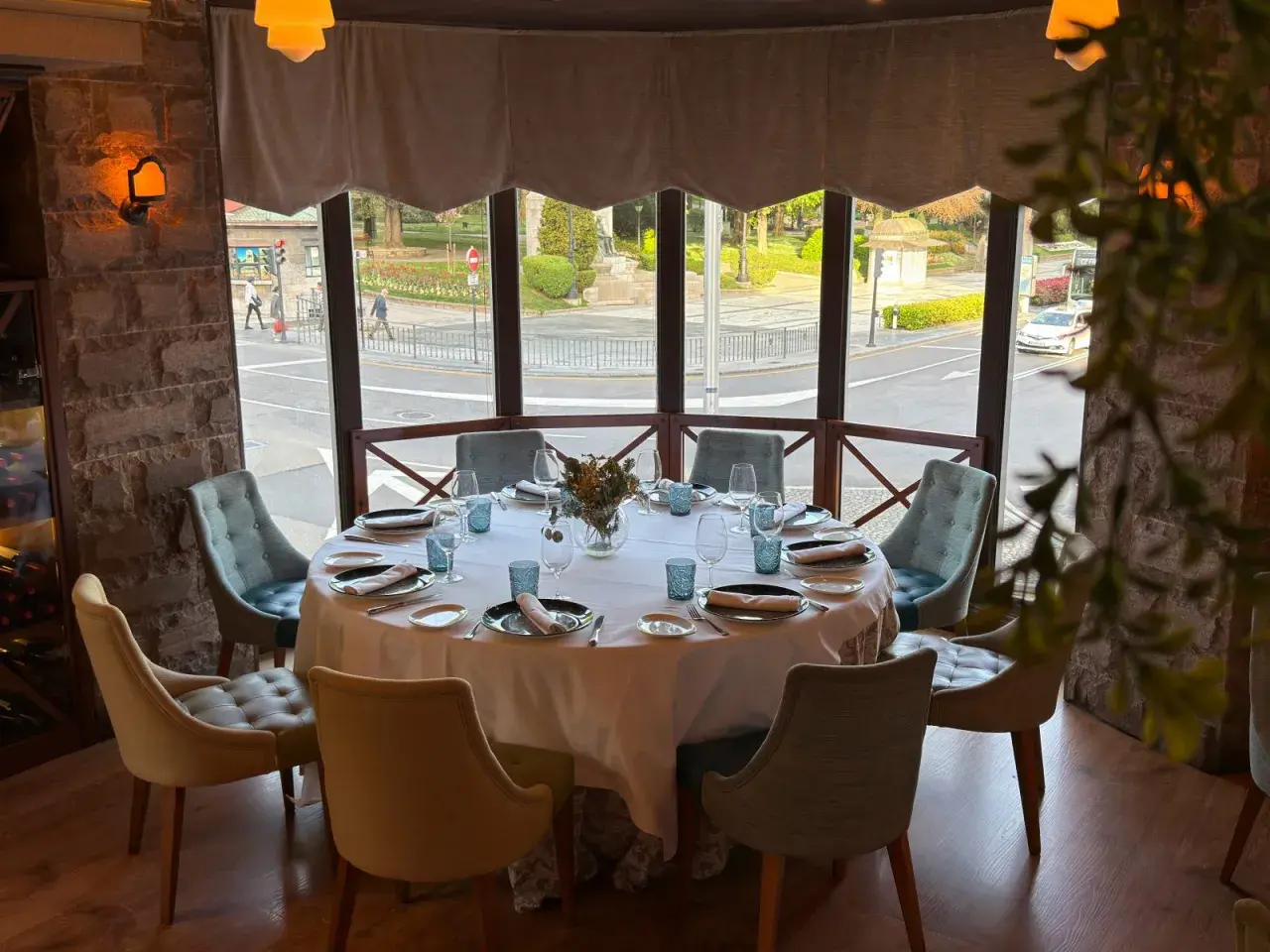 Mesa elegante lista para una cena en la corte de Pelayo, con vistas a la calle y un parque.