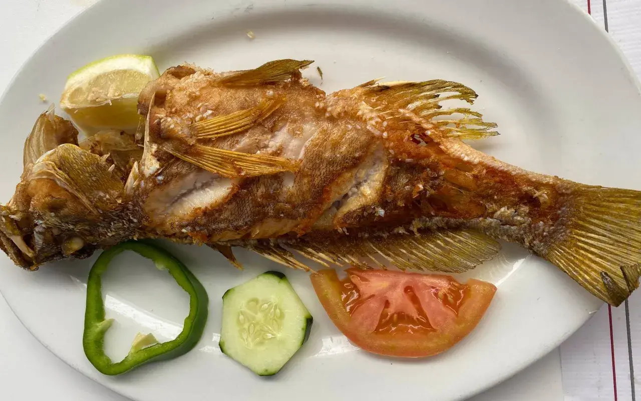Pescado frito entero, servido con rodajas de limón, pimiento verde, pepino y tomate. ¡Una excelente opción de donde comer en El Hierro!