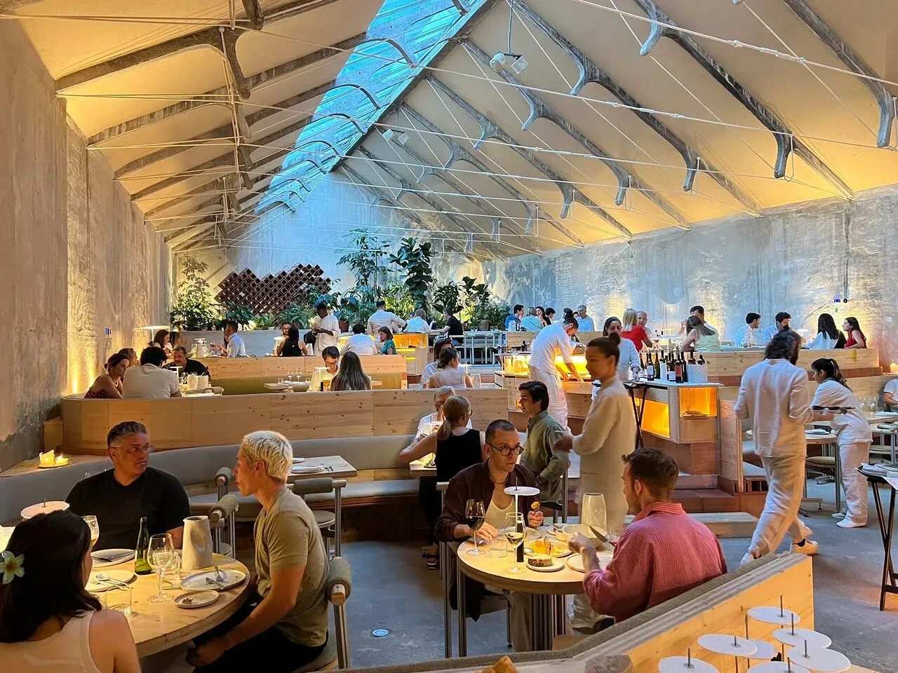 Gente cenando en un moderno espacio tramo Madrid, con techos altos y luz natural.