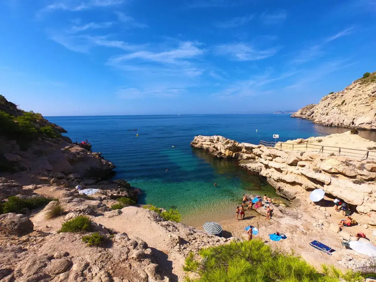 Un día soleado en el racó del conill, con gente disfrutando de las aguas cristalinas y la arena dorada.