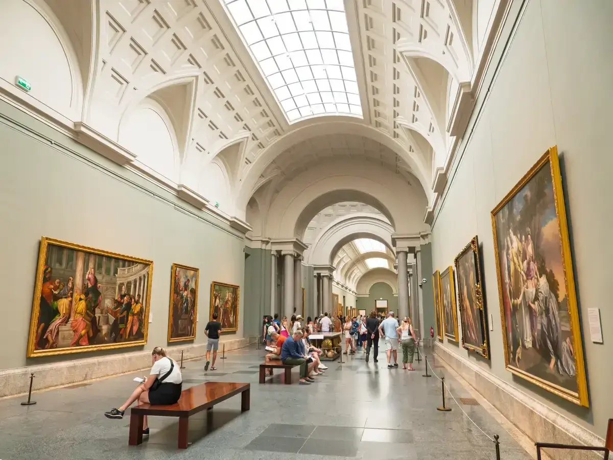 Gente disfruta del arte en un museo, celebrando el **18 de mayo, Día de los Museos**.