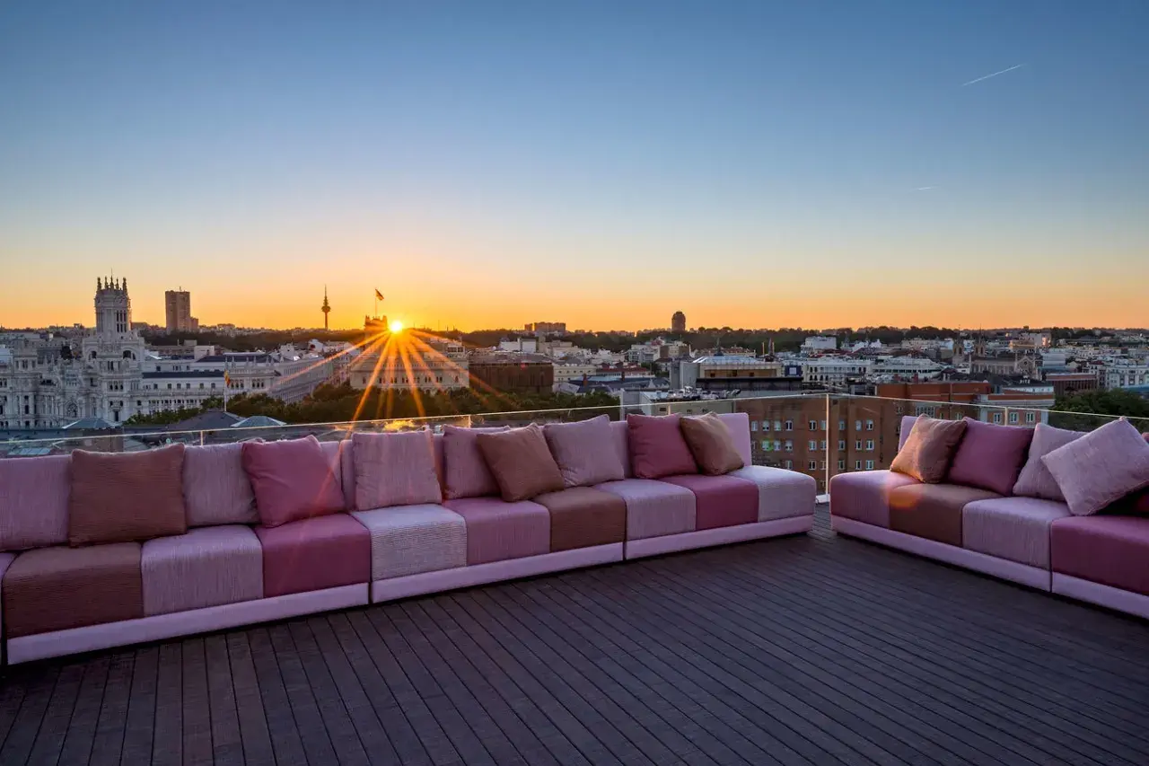 Sofás modulares rosas en una terraza con vistas a la ciudad al atardecer. Una casa suecia rooftop perfecta para disfrutar del sol.