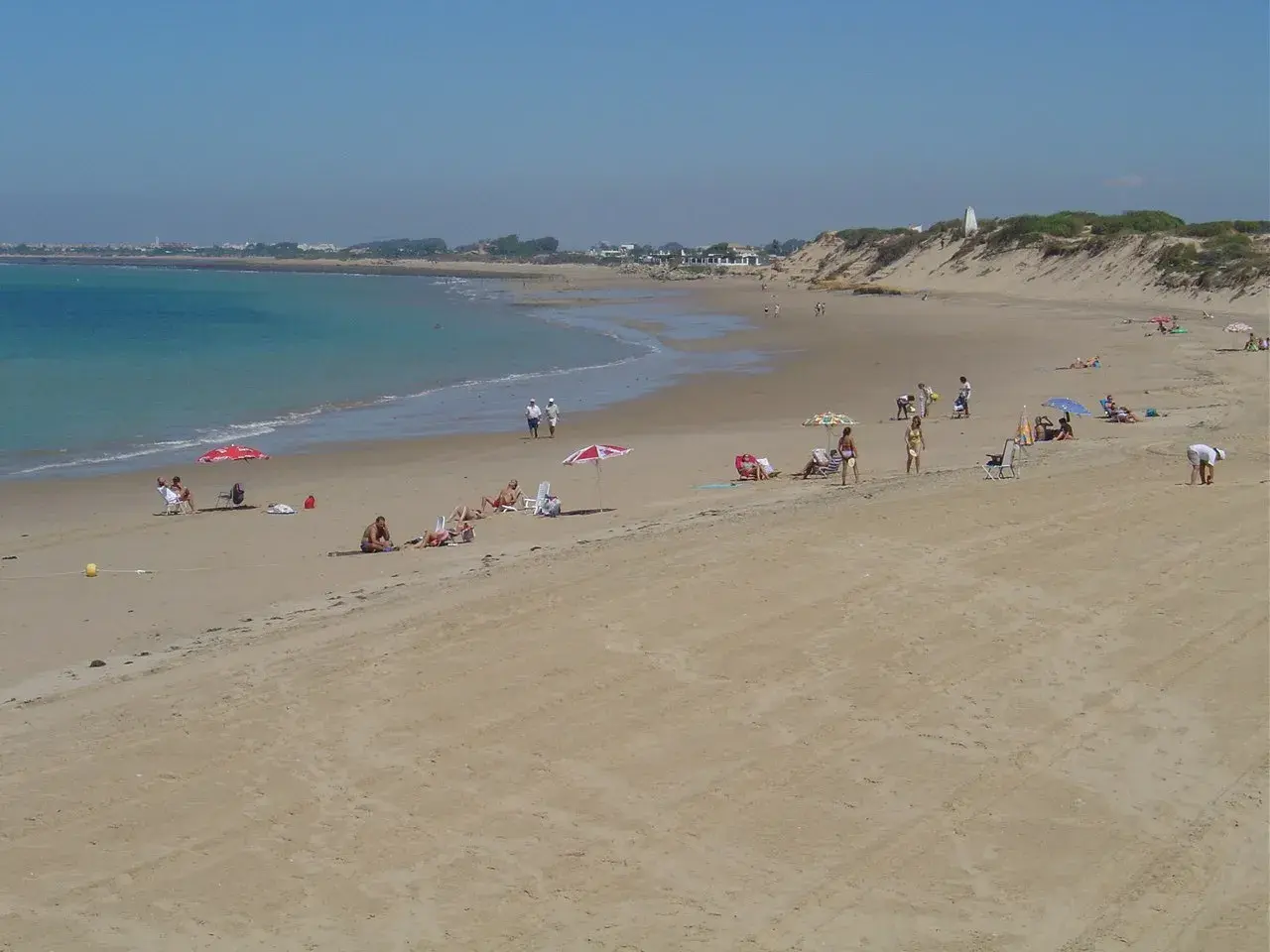 Gente disfruta del sol en la playa de Punta Candor, Rota. ¡Un lugar ideal para relajarse y leer opiniones positivas!
