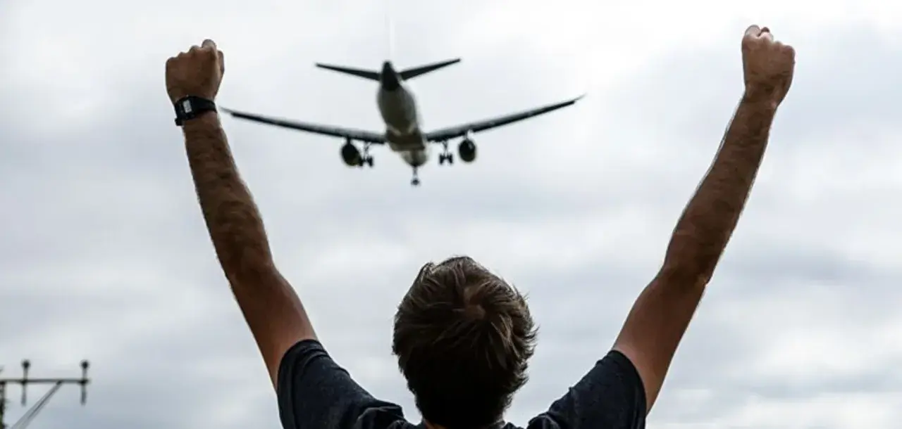 Persona con brazos en alto celebra la llegada de un avión en el mirador de aviones de El Prat.
