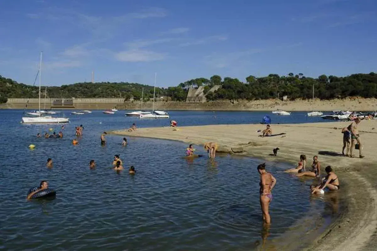 Gente disfrutando de un día soleado en la playa, ¡quién diría que en Madrid hay playa! Barcos y bañistas en un día perfecto.