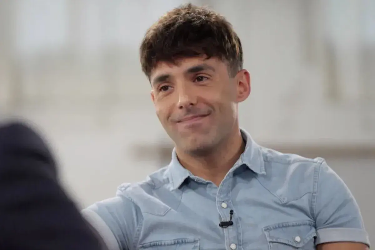 Un hombre sonríe, con su camisa vaquera y un micrófono. Podría ser el mago pop de Madrid.