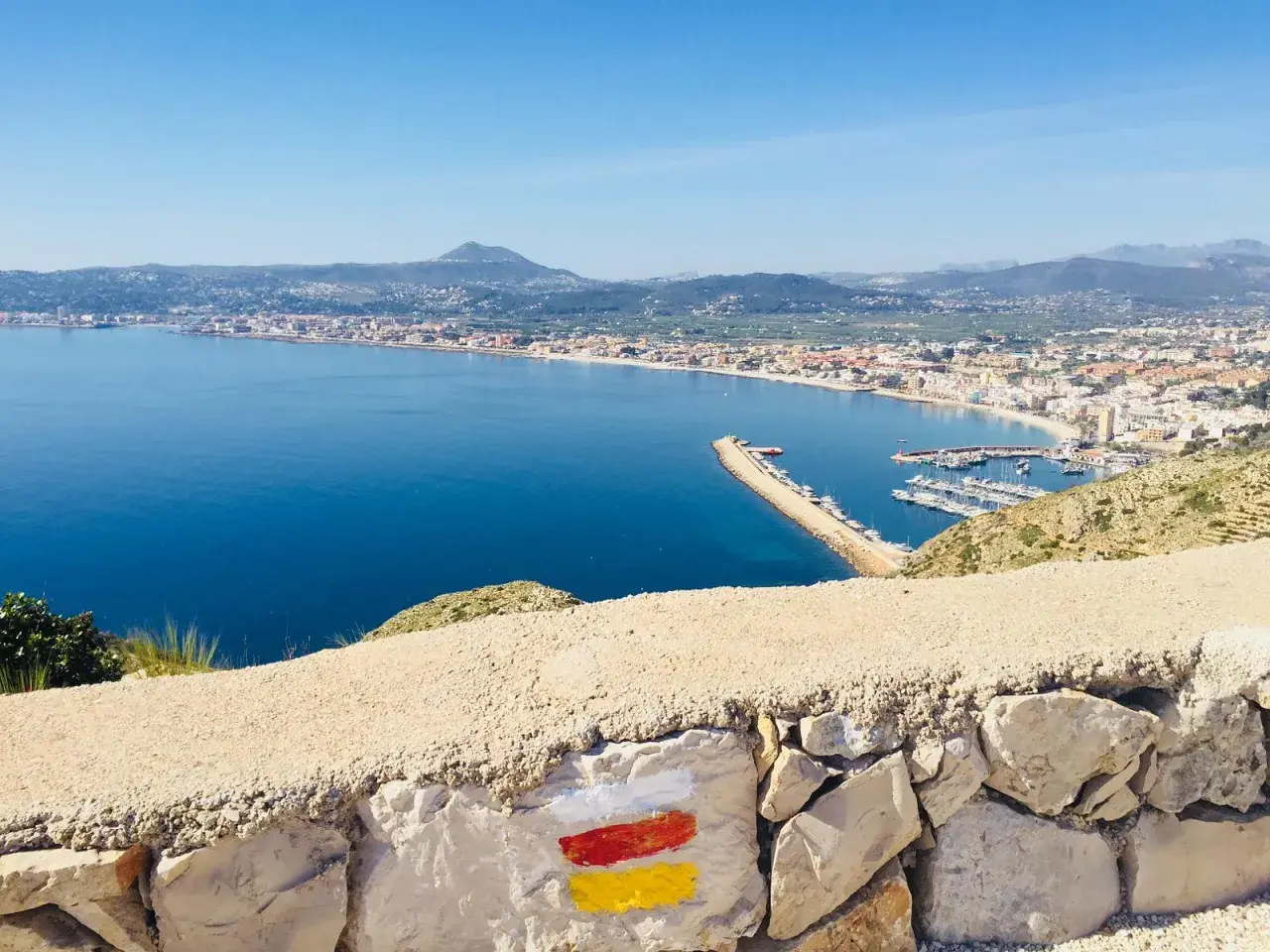 Vista panorámica de la bahía y el puerto deportivo, con el faro del Cabo de San Antonio al fondo.