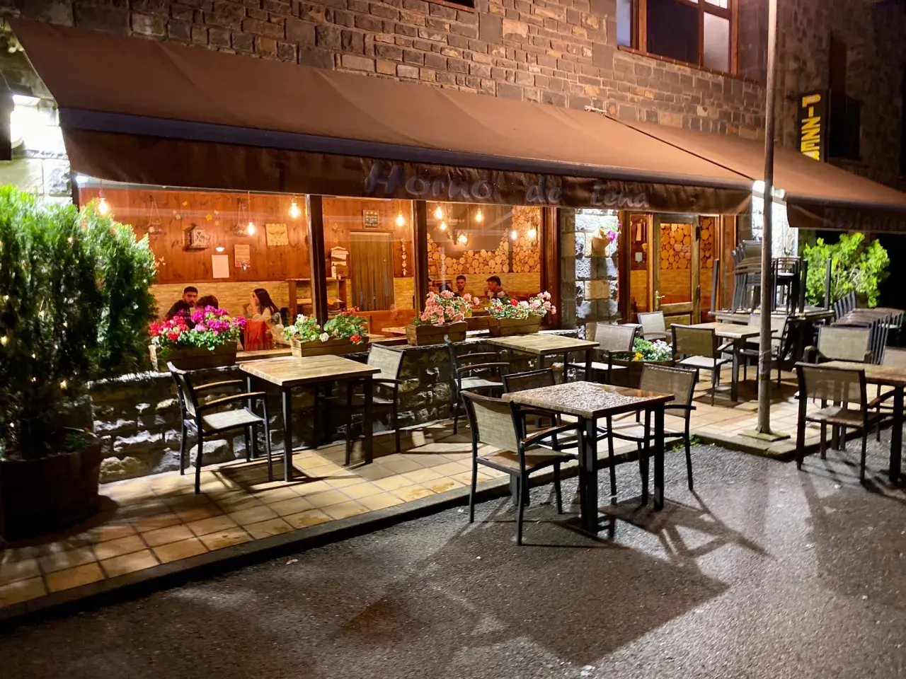 Restaurante "Horno de Lena" en Broto, con mesas al exterior y gente cenando. Ideal para saber donde comer en Broto.