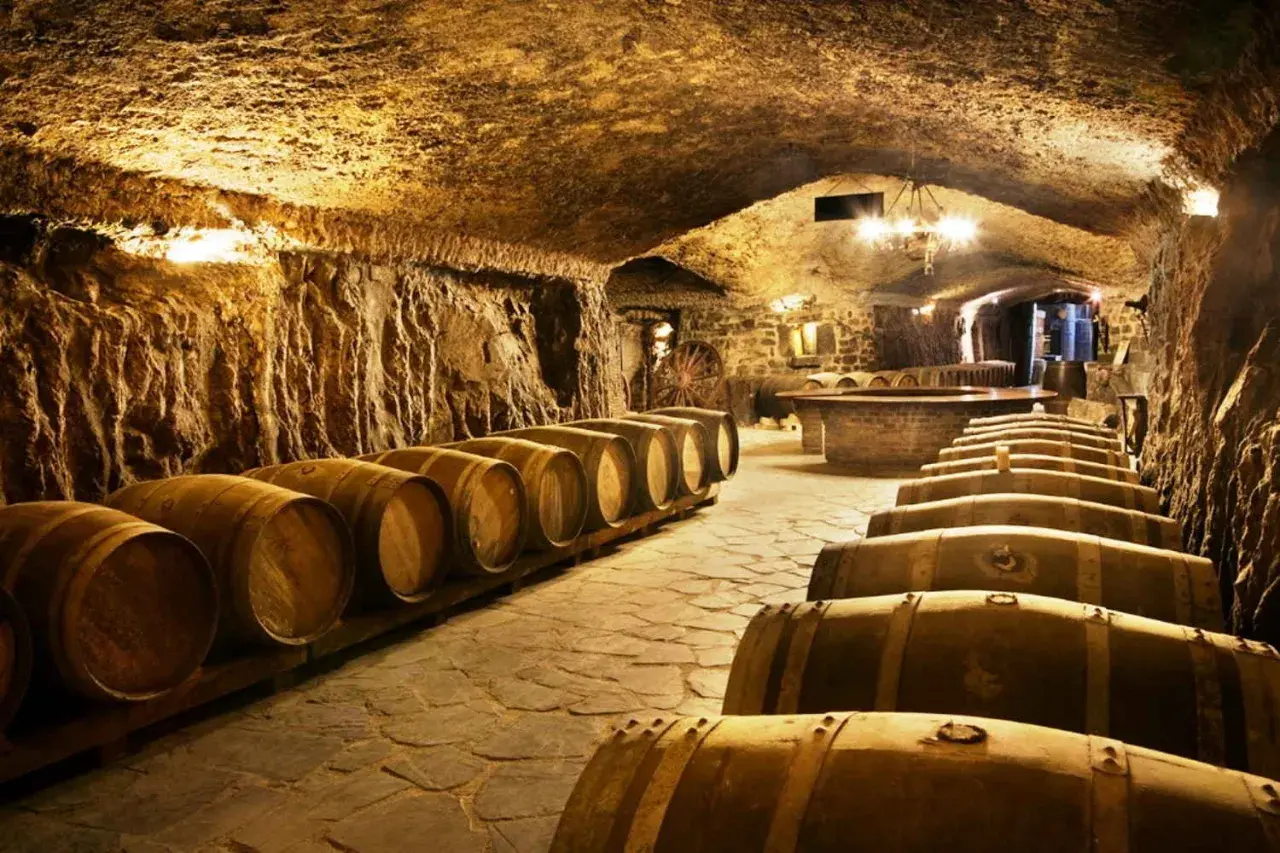 Antiguas barricas de roble esperan en esta bodega subterránea, perfecta para una visita a bodegas.