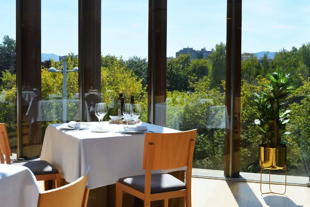 Elegante mesa puesta en un restaurante con vistas a la naturaleza, ideal para descubrir los mejores restaurantes en pueblos cerca de Pamplona.