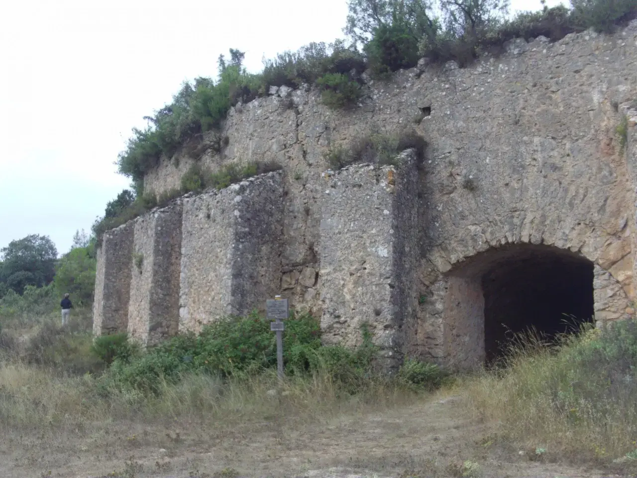 Antigua construcción de piedra en la Serra de Mariola, con un arco de entrada y vegetación circundante.