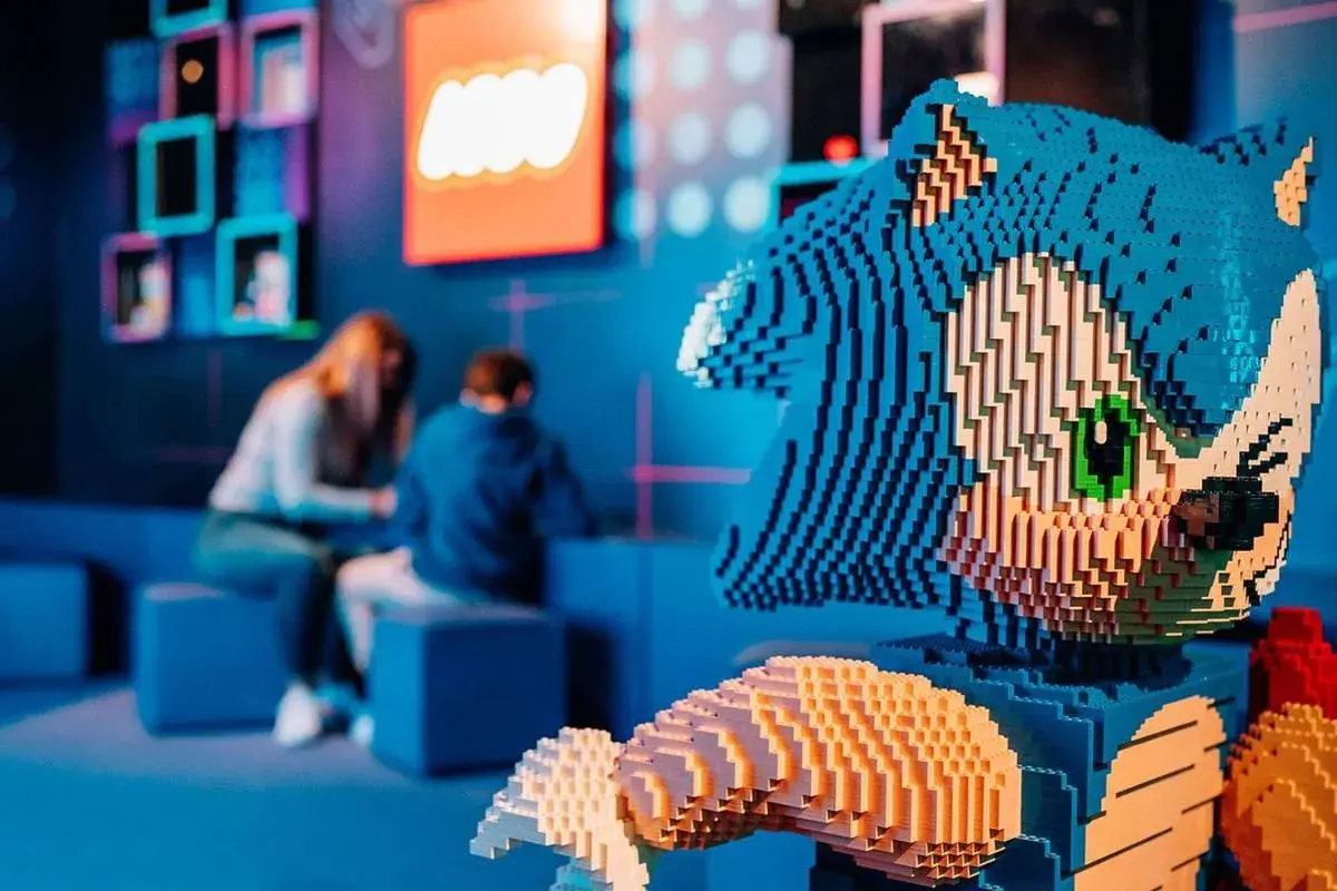 Figura de Sonic hecha de LEGO en el museo LEGO de Madrid. Al fondo, dos personas observan una exposición.