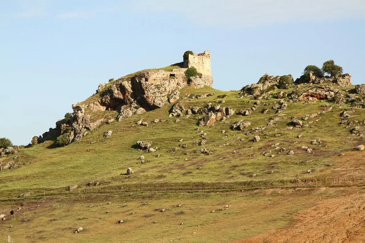 Ruinas de un castillo en una colina rocosa, un paisaje que evoca la historia de Navas de Tolosa, donde está.