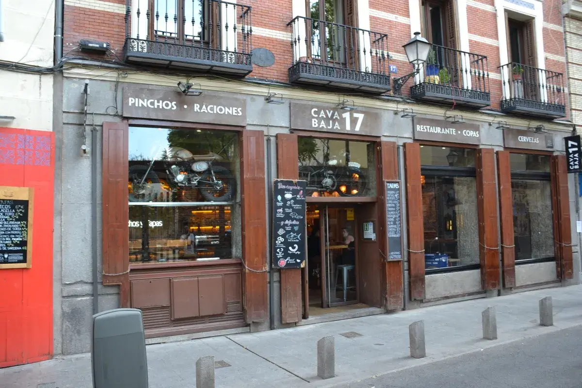 Fachada de Cava Baja 17, un restaurante con una moto vintage expuesta en el escaparate.