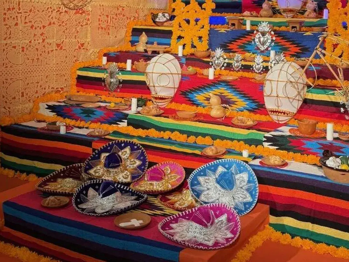 Un vibrante altar de los muertos en una casa de México, adornado con sombreros, flores de cempasúchil y ofrendas.