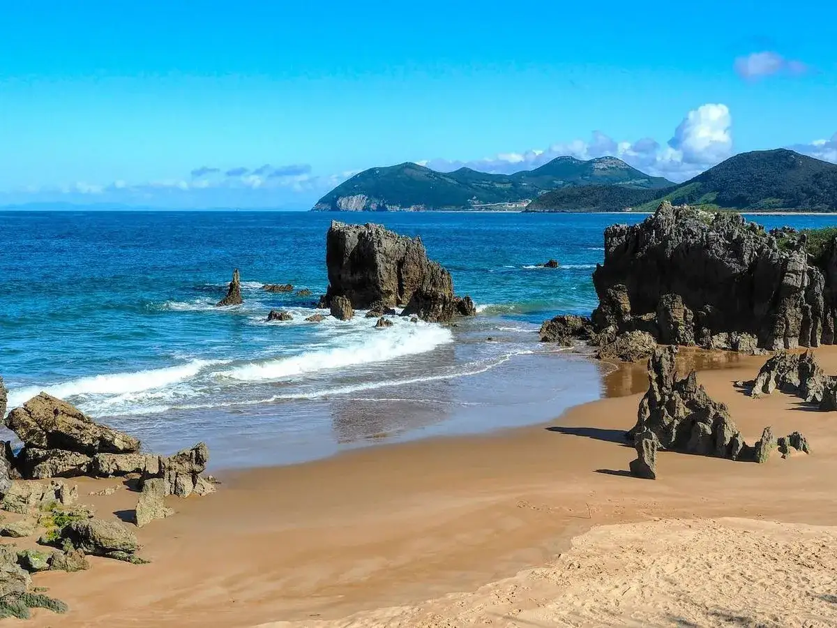 Playa de Arcisero, un lugar incre&iacute;ble que ver en Isla, Cantabria. Rocas y mar azul en un d&iacute;a soleado.