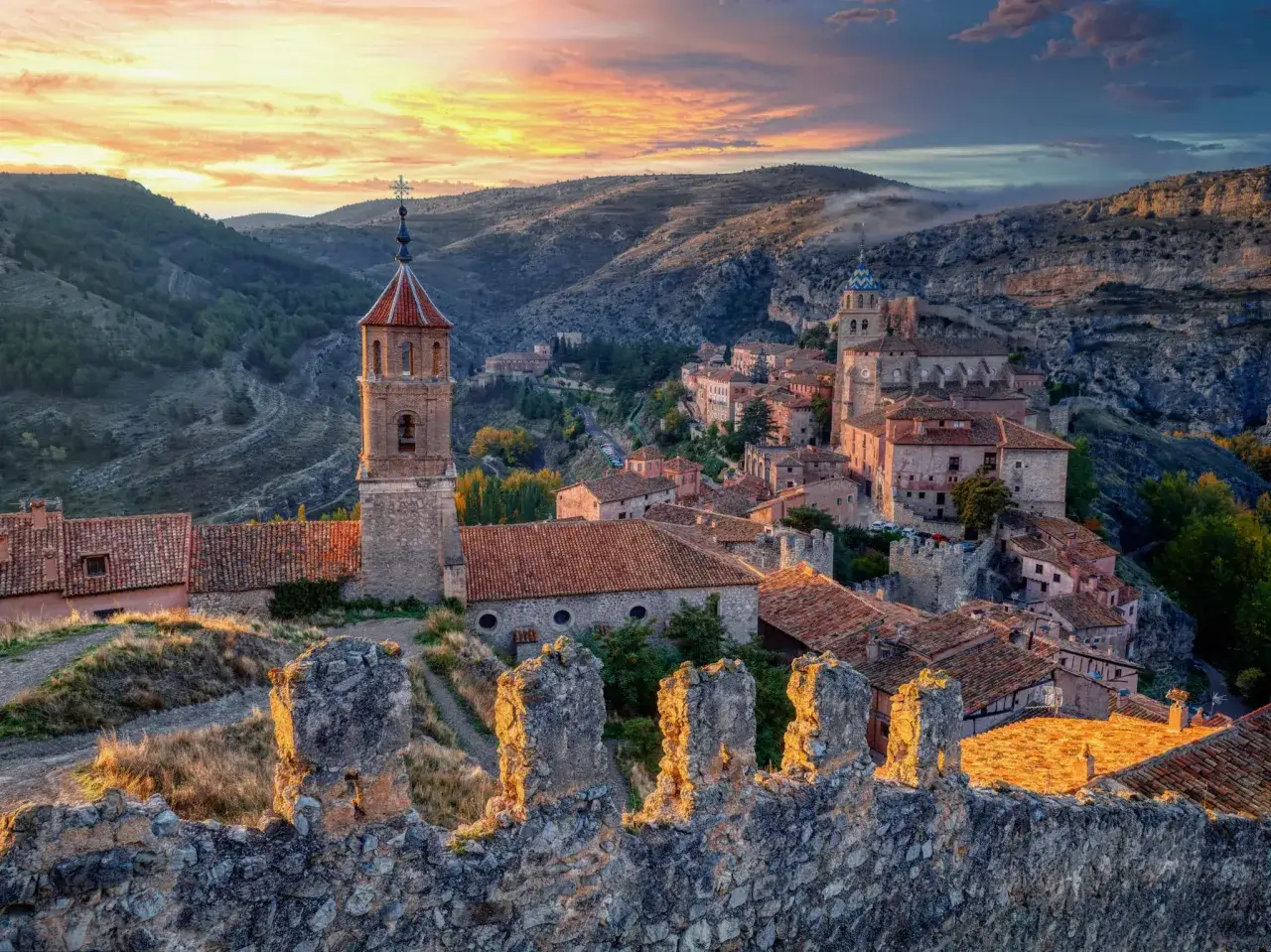 Atardecer sobre un pueblo medieval, uno de los pueblos bonitos cerca de Sos del Rey Católico, con tejados de teja y torres de iglesias.